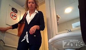 Женщина в синем костюме писает в туалете